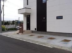 コンクリート舗装の四角いくり抜きに芝生を植えた駐車場　加須